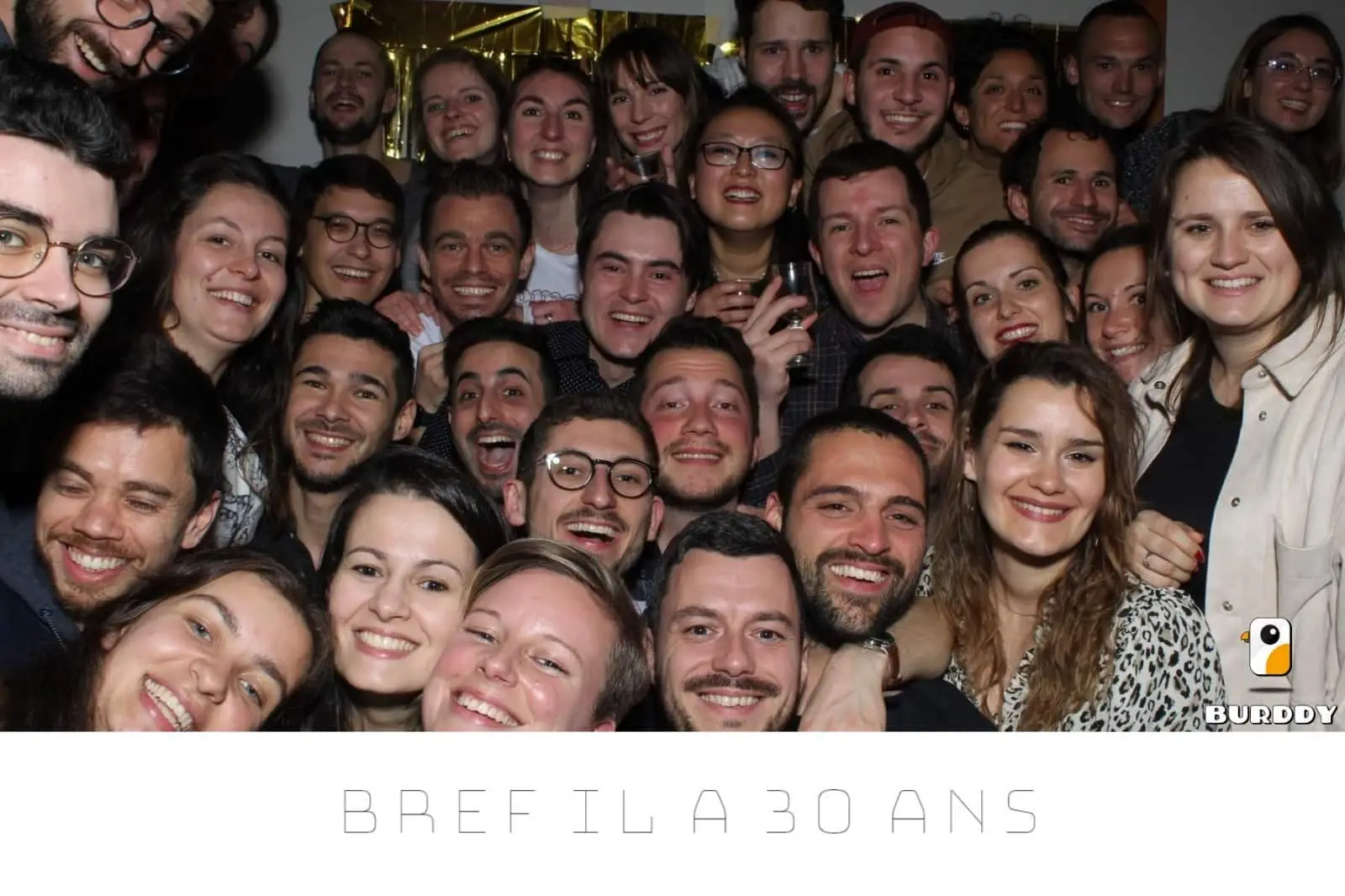 Un groupe d'amis prend la pose devant le photobooth Burddy